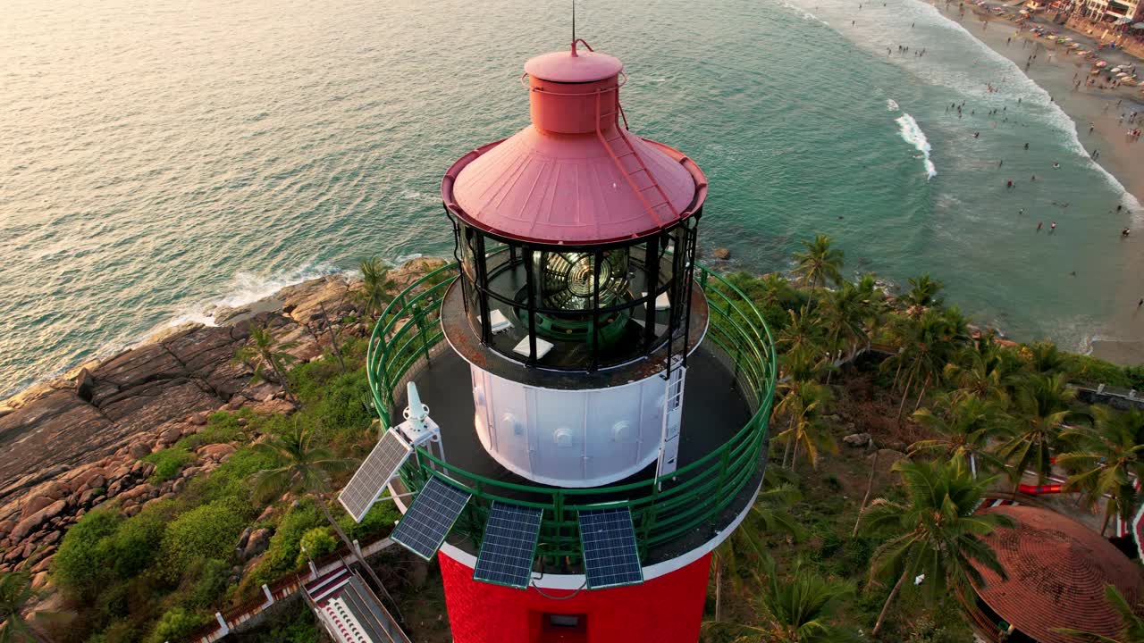 日落时岩石海岸线上的灯塔塔，鸟瞰图。印度喀拉拉邦的Kovalam海滩和灯塔。视频下载