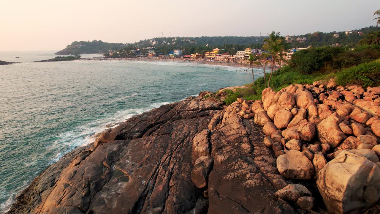 鸟瞰碧绿的海浪撞击岩石海岸线，大海在布满巨石的海岸线周围编织。Kovalam海滩，印度喀拉拉邦。视频下载