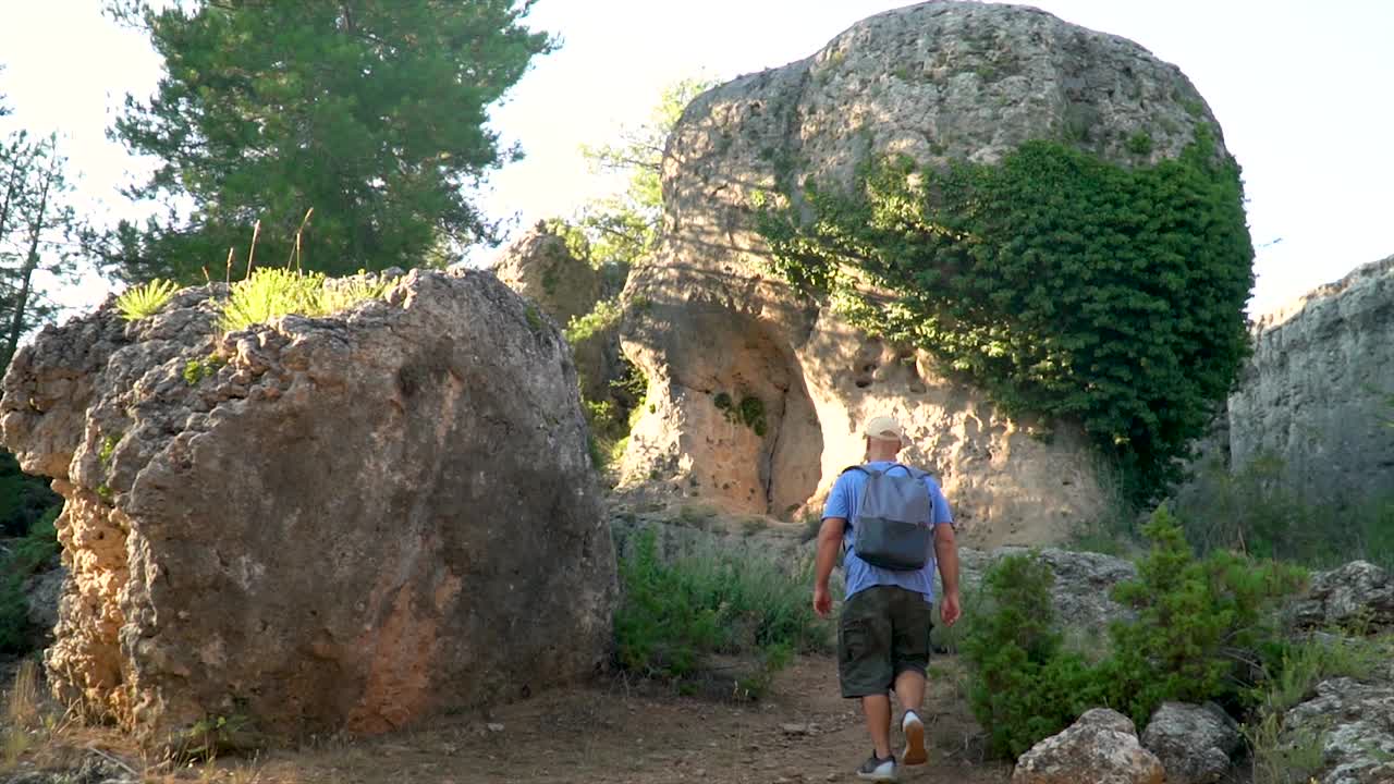 慢镜头，夏日夕阳下，一名男子在森林里与岩石徒步旅行视频素材