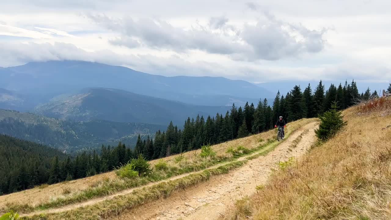 骑电动山地车的人沿着山上长满草的小路在户外骑行。视频素材