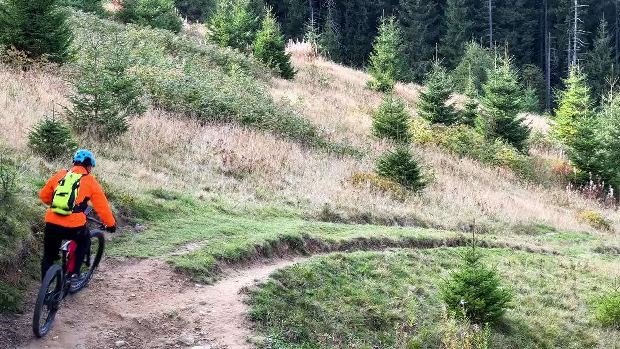 骑电动山地车的人沿着山上长满草的小路在户外骑行。视频素材