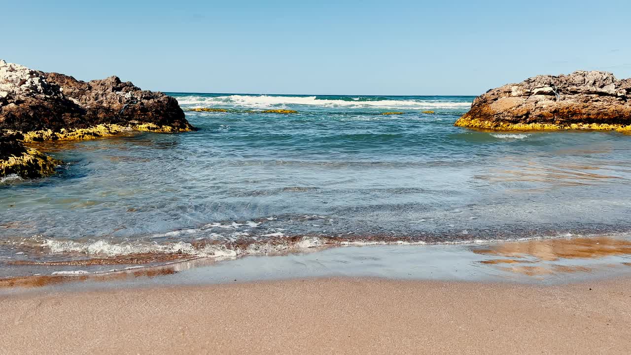 阳光明媚的一天，海浪冲击着岩石视频下载