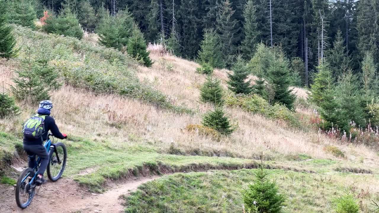 骑电动山地车的人沿着山上长满草的小路在户外骑行。视频素材