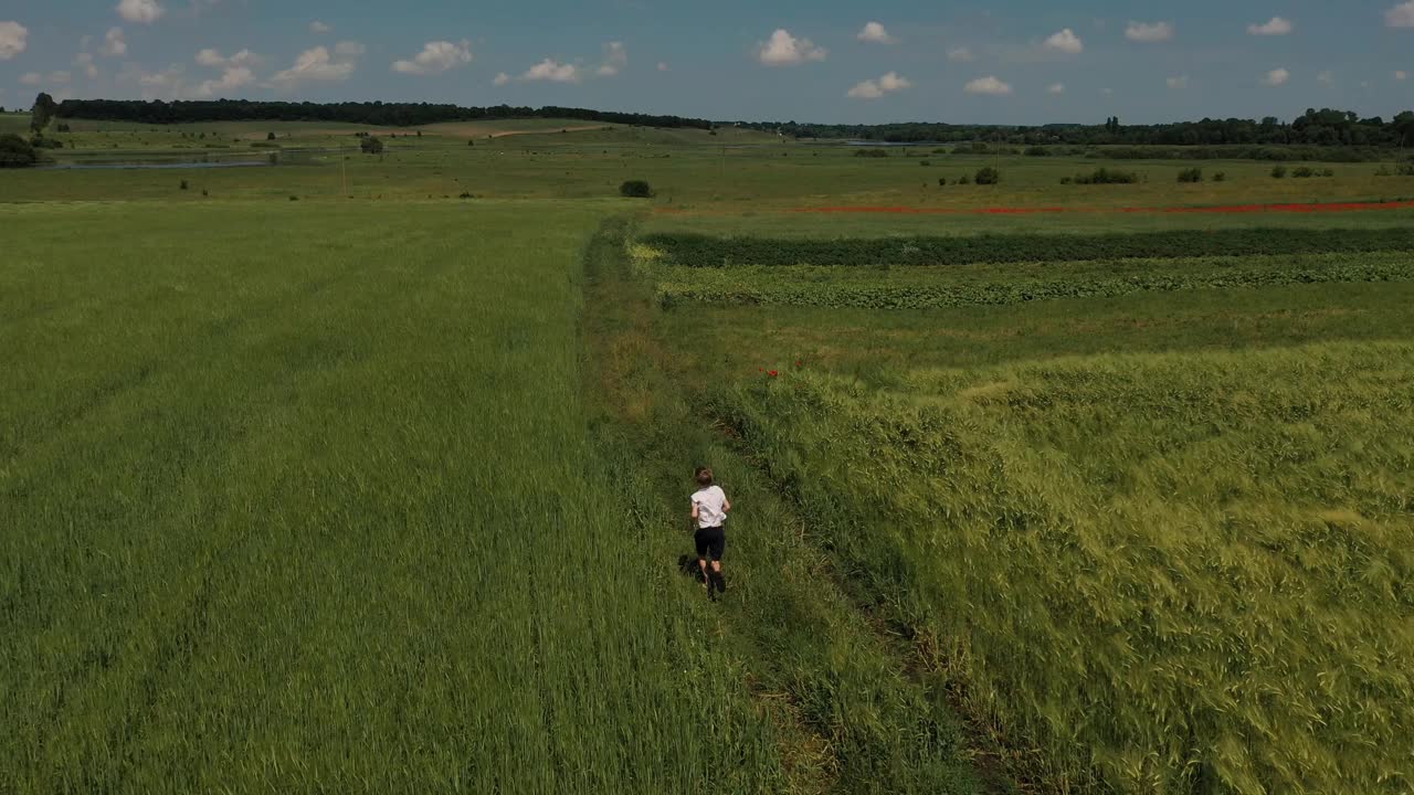 小男孩独自在绿色的草地上奔跑鸟瞰图4k。视频下载