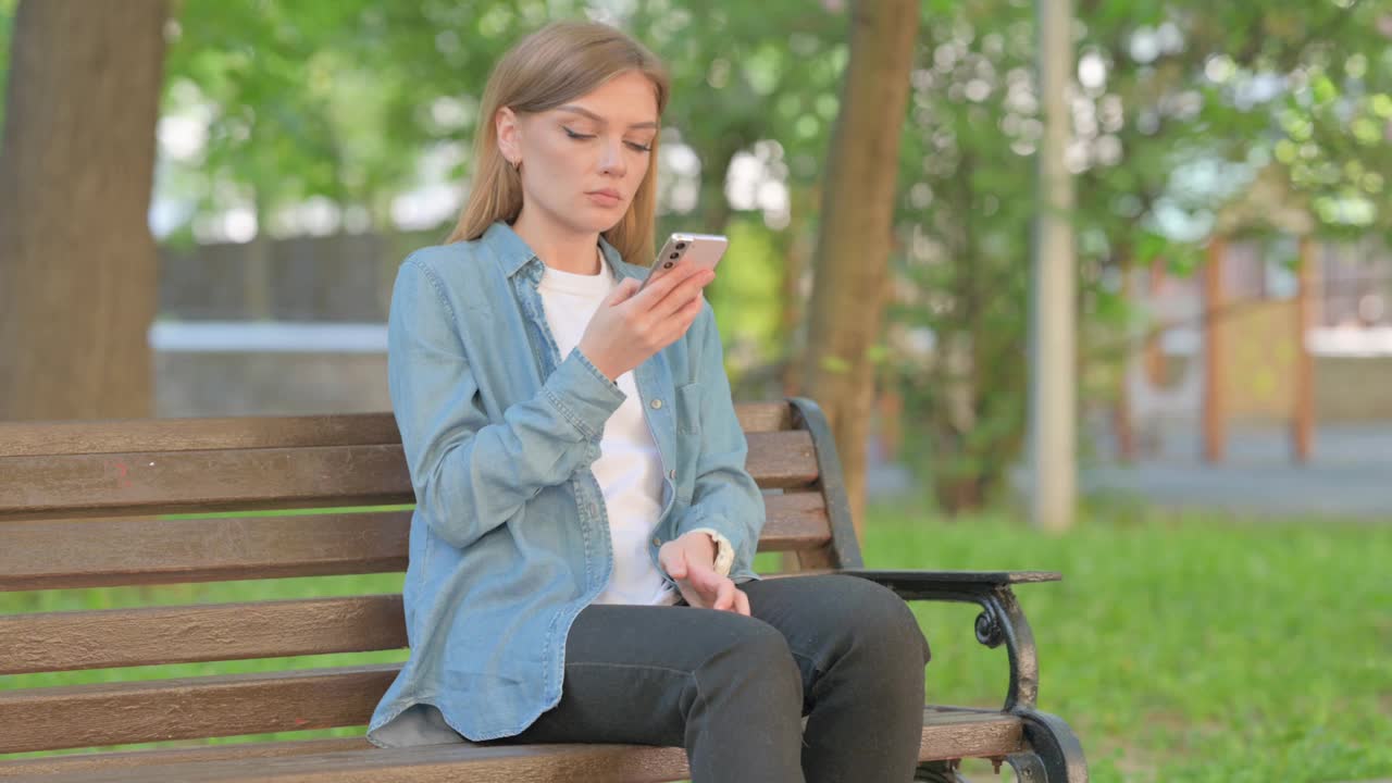 坐在户外打电话的年轻女子视频素材