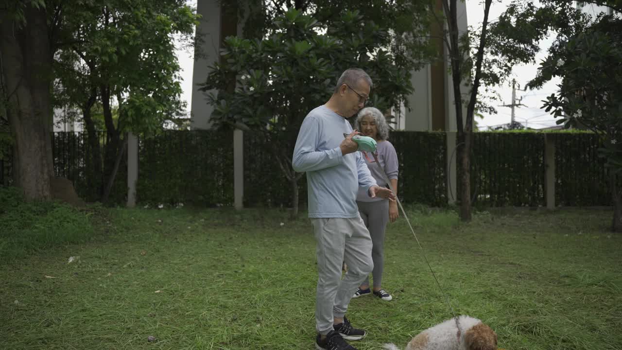 一对亚洲老年夫妇带着狗在公园散步视频下载