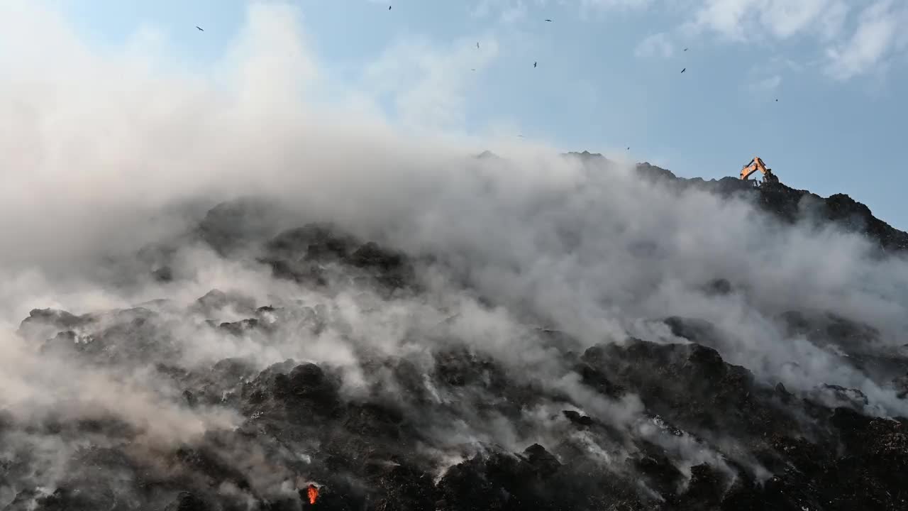 加济布尔垃圾填埋场火灾产生的有毒烟雾污染空气，因为鸟类飞过头顶视频素材