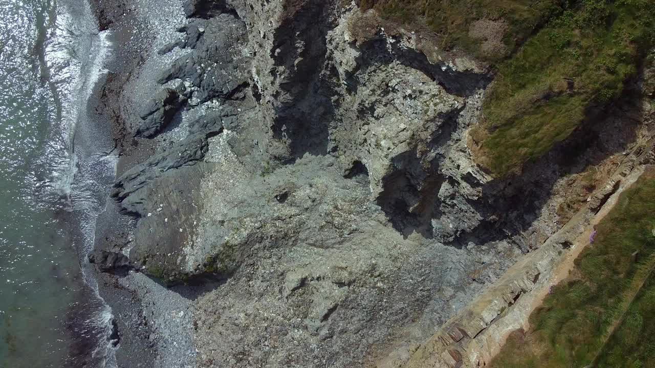 海岸线是绿色植被和灰色岩石的混合体，形成了鲜明的对比。宁静而崎岖的自然景观。视频素材