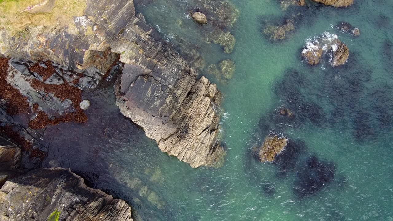 一个高海拔拍摄的戏剧性的海岸景观，锯齿状的岩石和清澈的浅水。视频素材