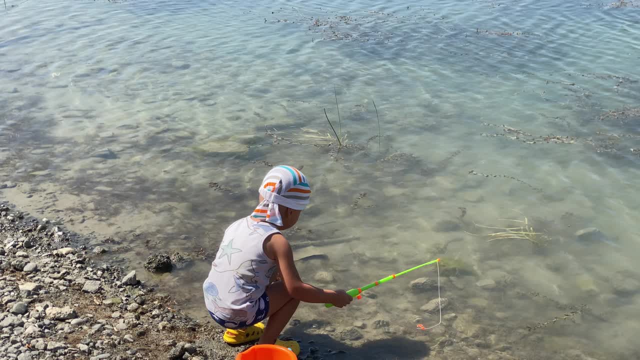 快乐的小渔夫在夏天玩着玩具鱼竿在湖里捉玩具鱼视频下载