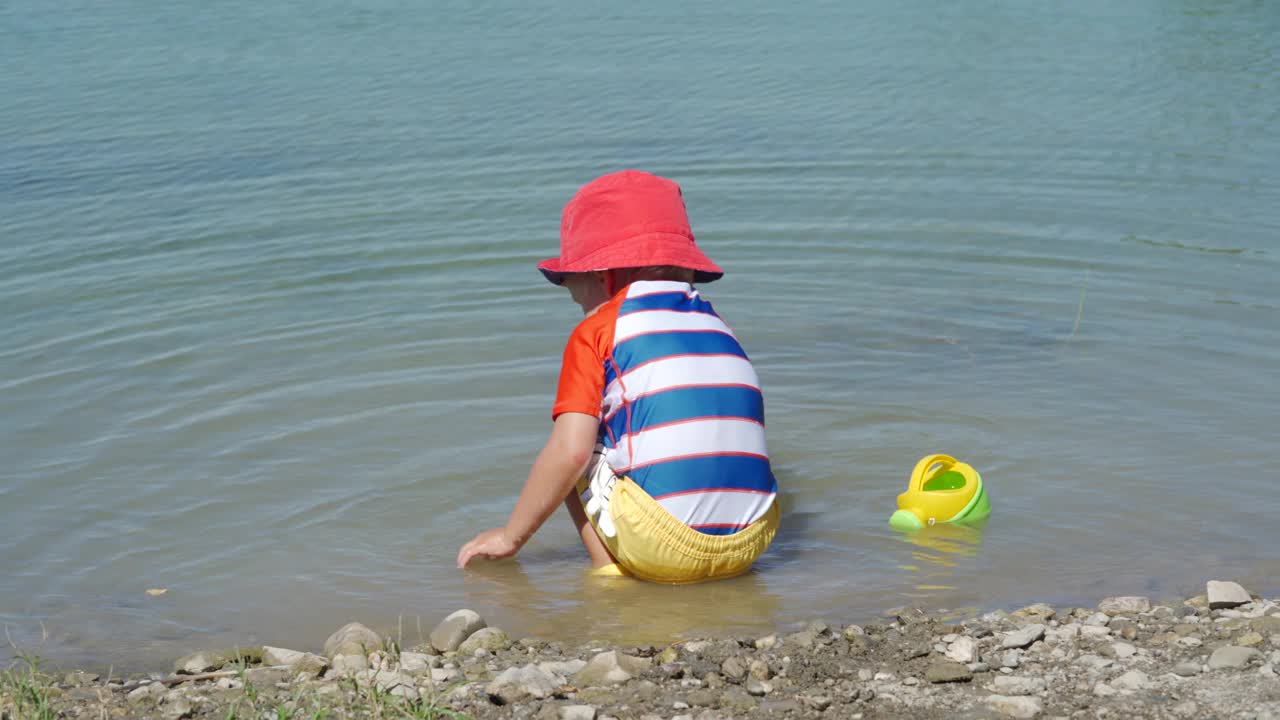 夏日里，穿着防晒服的小孩在湖边玩耍。视频下载