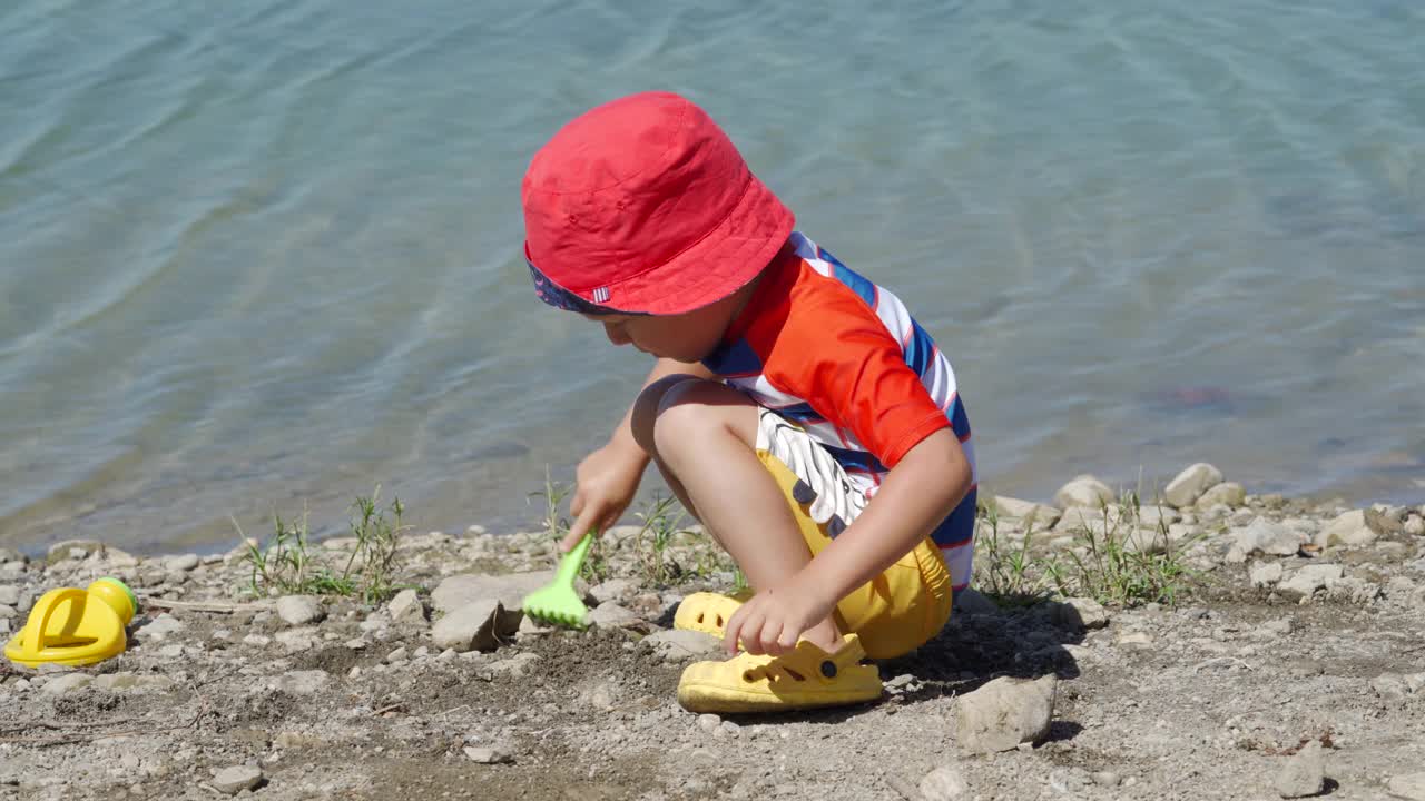 夏日里，穿着防晒服的小孩在湖边玩耍。视频素材