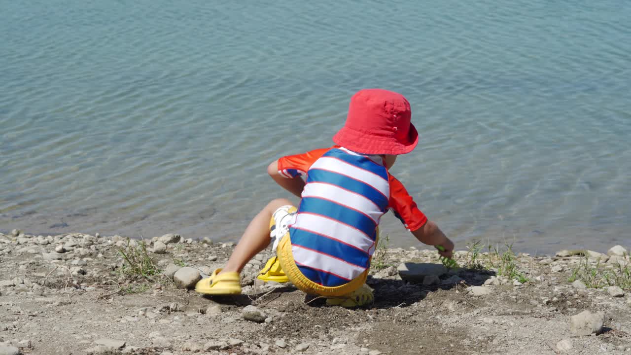 夏日里，穿着防晒服的小孩在湖边玩耍。视频素材