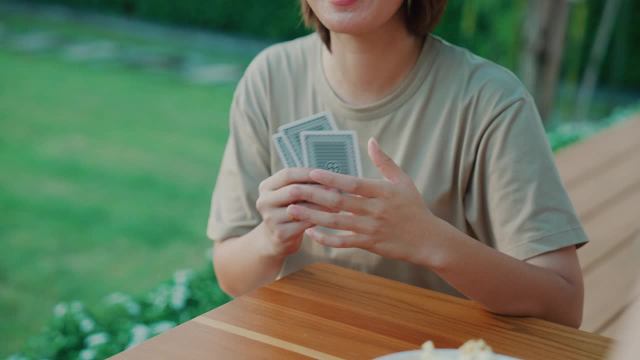 在一个家庭聚会上，年轻的亚洲男女在后院打牌。视频素材