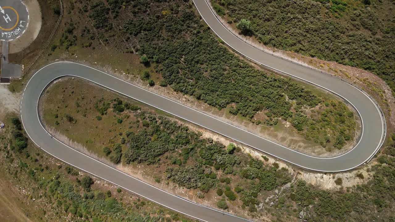 一辆汽车和一辆摩托车在曲折的乡村道路上的俯视图视频下载