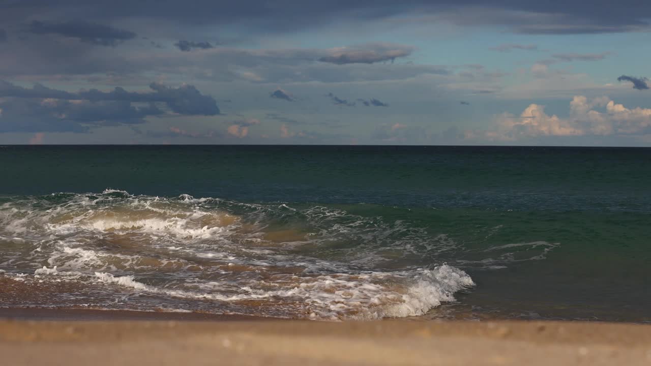 在美丽的金色午后阳光下，五彩缤纷的海岸波浪沿着海滩沙滩破碎，海鸥在上面飞翔。视频素材