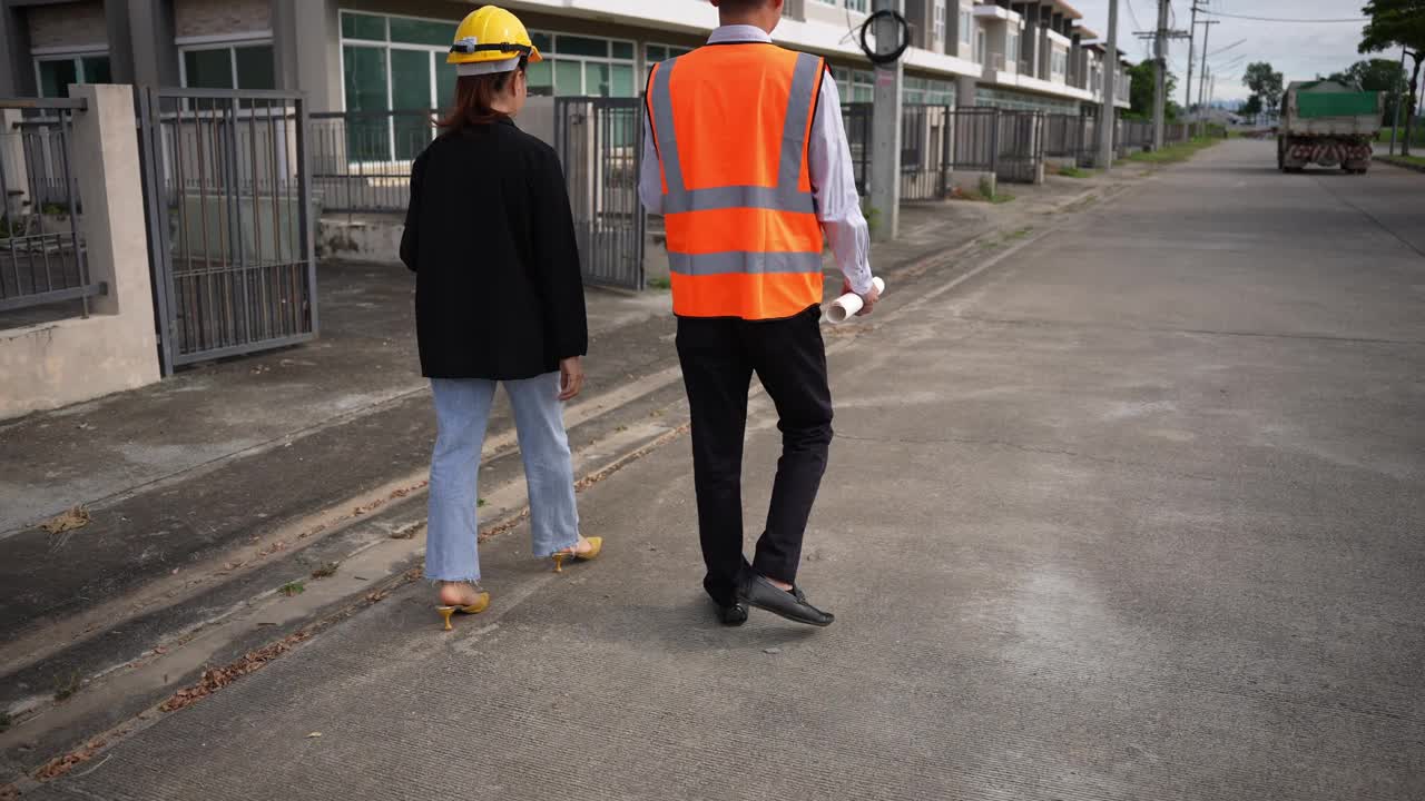 亚洲房地产商视察住宅项目年轻的建筑师夫妇在住宅建筑工地讨论和观看蓝图。视频素材