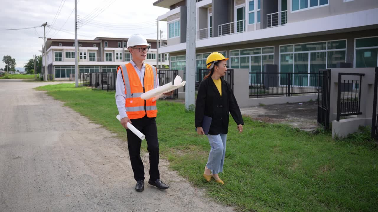 亚洲房地产商视察住宅项目年轻的建筑师夫妇在住宅建筑工地讨论和观看蓝图。视频下载