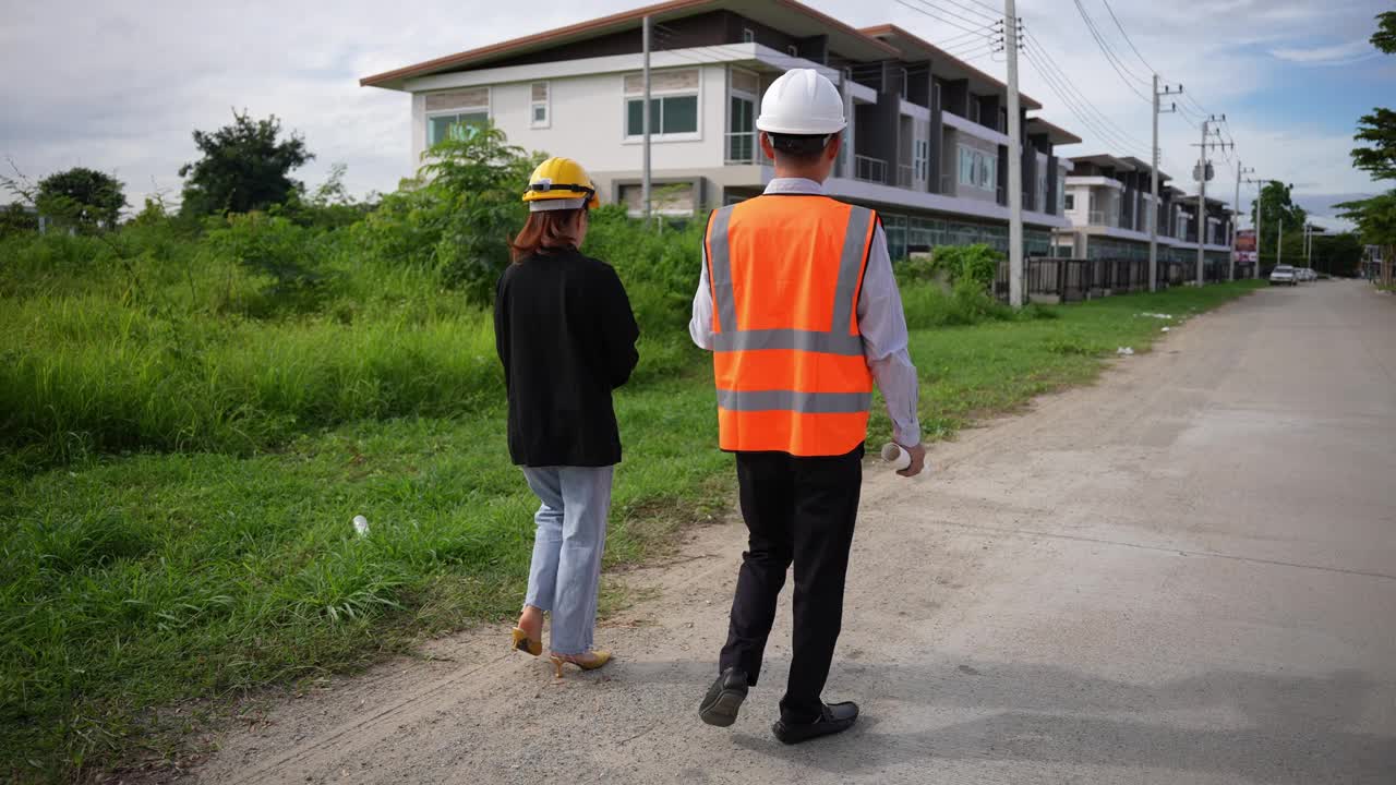 亚洲房地产商视察住宅项目年轻的建筑师夫妇在住宅建筑工地讨论和观看蓝图。视频素材