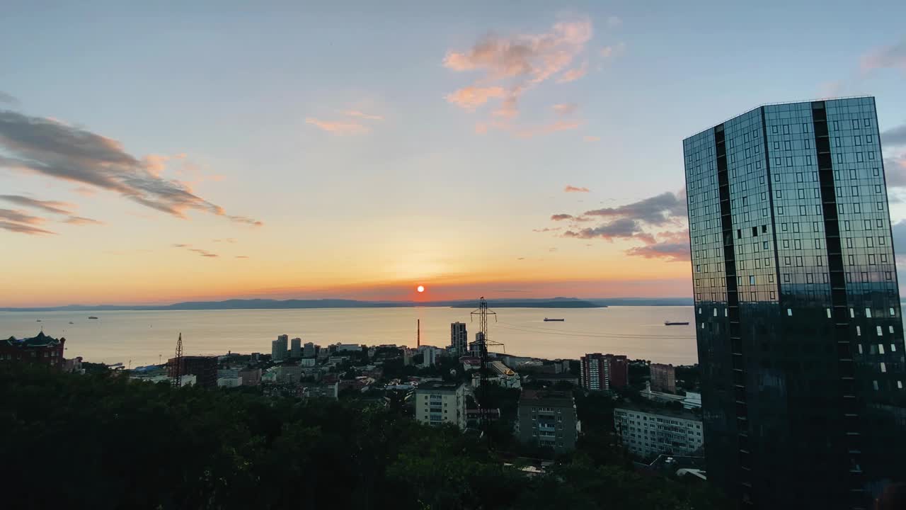 这个美丽的海滨大城市是在日落时拍摄的。相机平滑地从日落和城市过渡到天空。视频素材