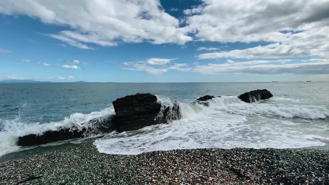 大海的波浪被岸边的一块大石头美丽地冲刷着。拍摄海水的动态和慢动作。平滑的摄像机移动视频下载