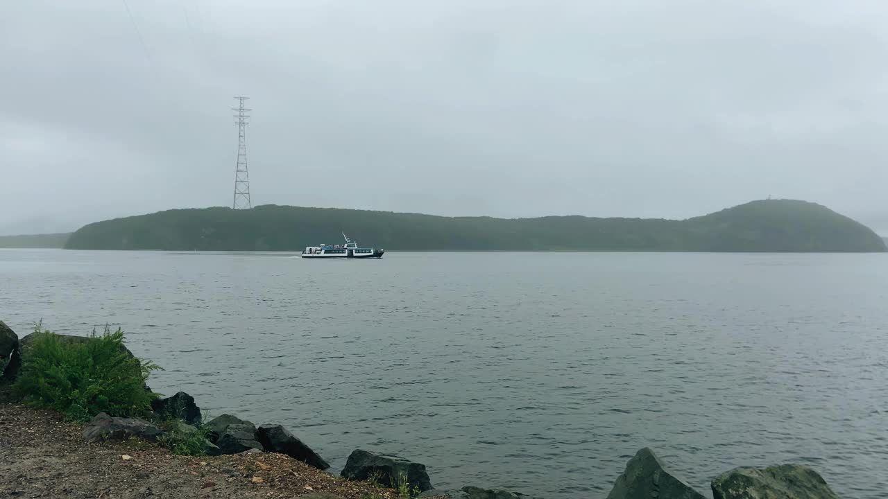 一艘小船驶过海岸附近的海湾。摄影机在船的后面流畅地移动视频下载