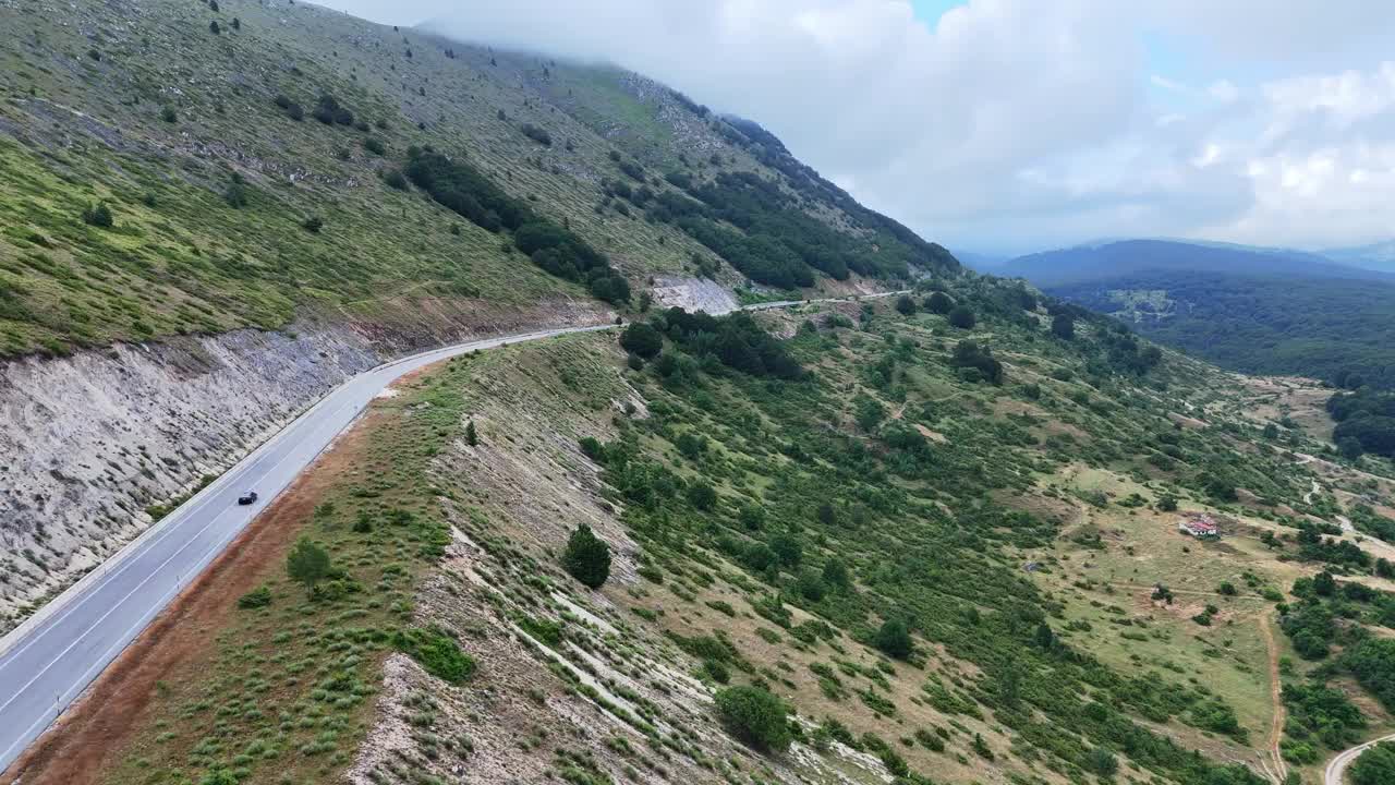 令人惊叹的鸟瞰图:在阴天，一条蜿蜒的山路被郁郁葱葱的青山环绕视频素材