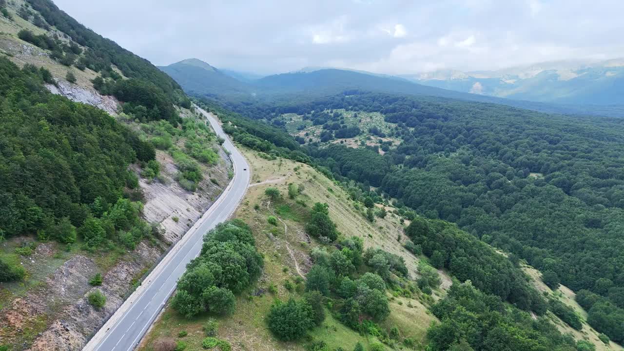 雄伟的山路蜿蜒穿过郁郁葱葱的青山在柔和的多云的天空视频素材