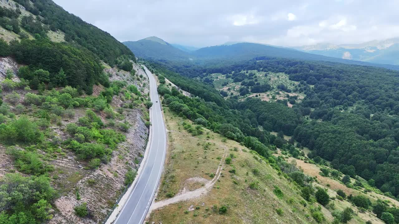 在柔和的晨光下，蜿蜒的山路蜿蜒穿过郁郁葱葱的绿色景观视频素材