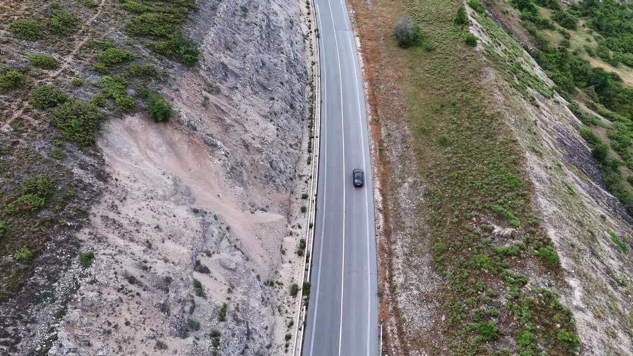 柔软的云下蜿蜒的山路，一辆汽车在绿色的山丘上行驶视频素材