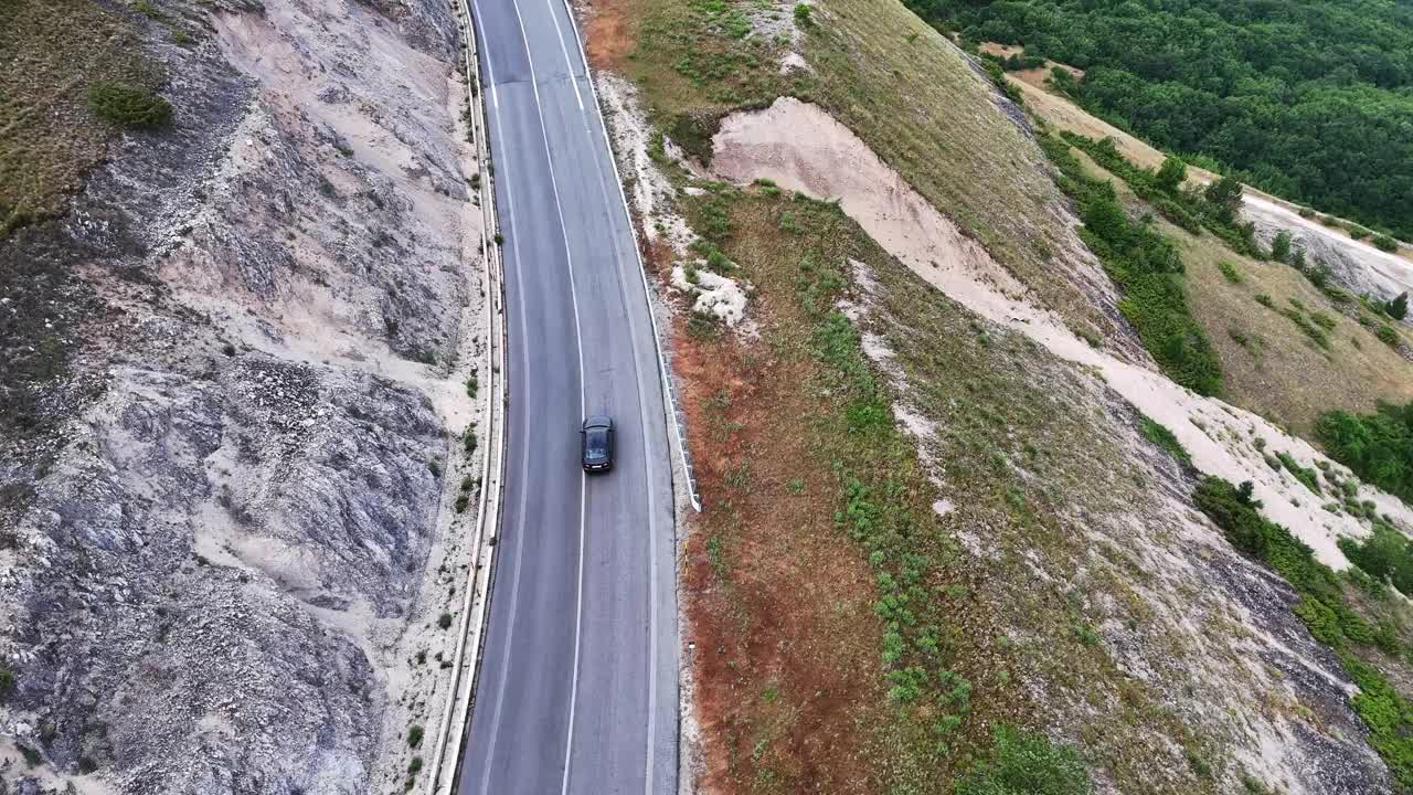 柔软的云下蜿蜒的山路，一辆汽车在绿色的山丘上行驶视频素材