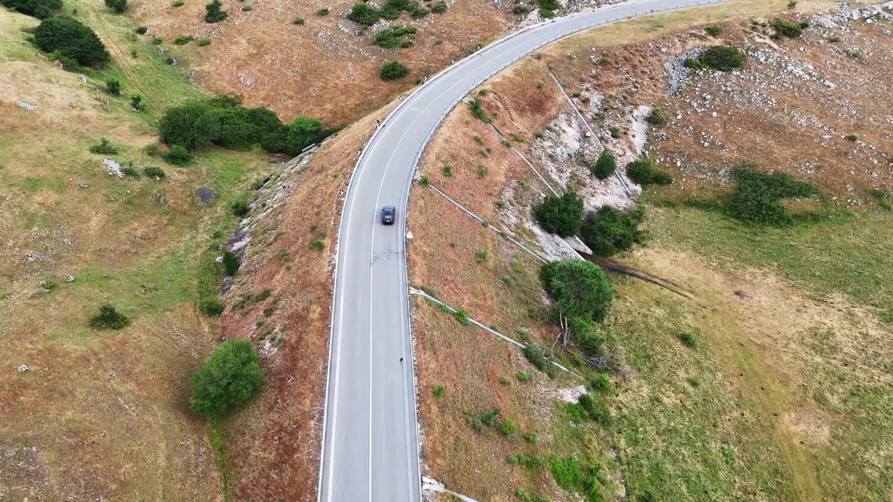 夕阳下蜿蜒的道路穿过生机勃勃的青山，一辆孤独的汽车驶过视频素材