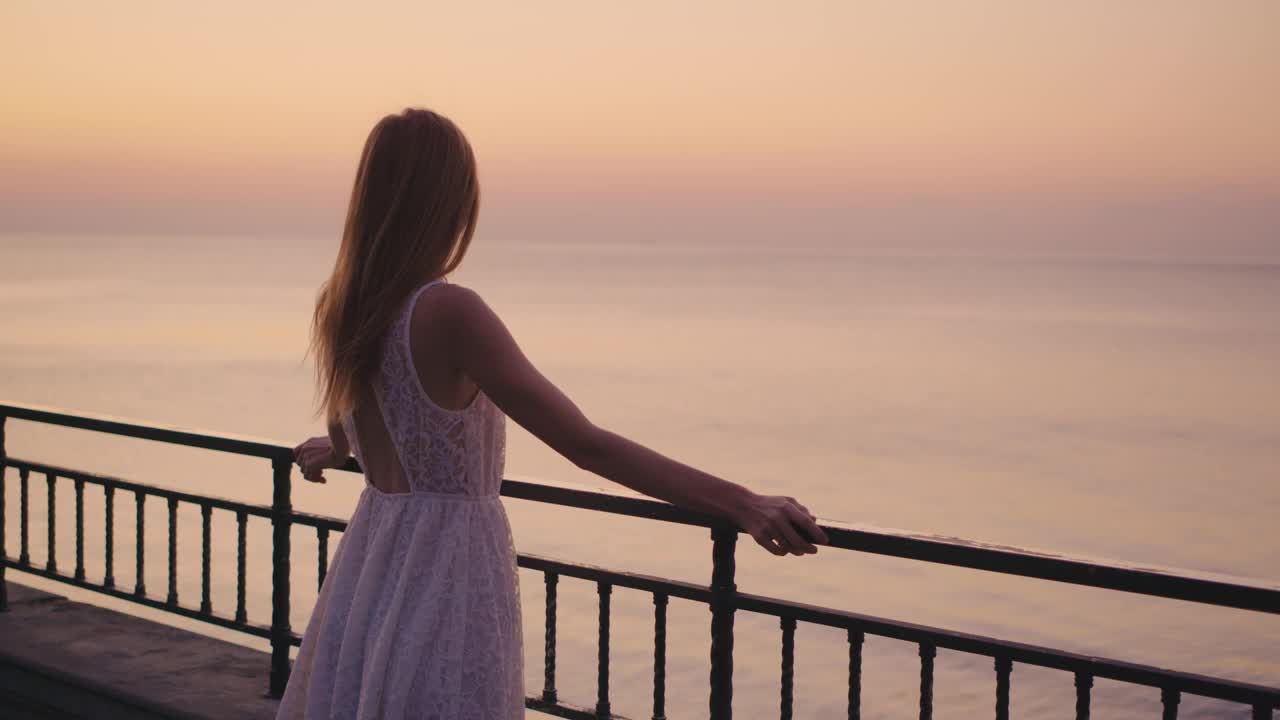 一个沉思的年轻女子凝视着黄昏宁静的大海，真正沉浸在大自然的美丽中，享受着夜晚的宁静时刻视频下载