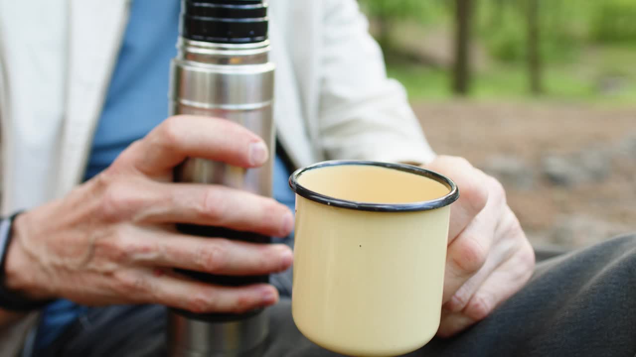 老人把保温瓶里的茶倒进金属杯子里视频素材