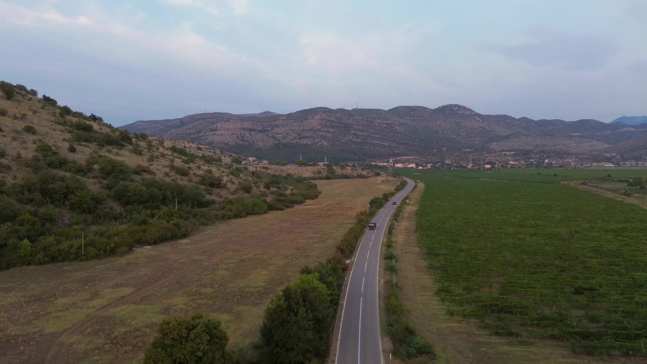 鸟瞰图:卡车和汽车行驶在道路上通过葡萄园田丘陵地形视频下载