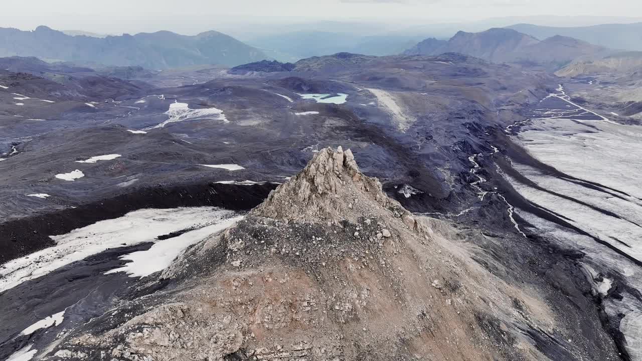 陡峭的山峰是一座古老的岩石山，高耸在布满火山岩和冰川的死气沉沉的田野上。鸟瞰图视频下载