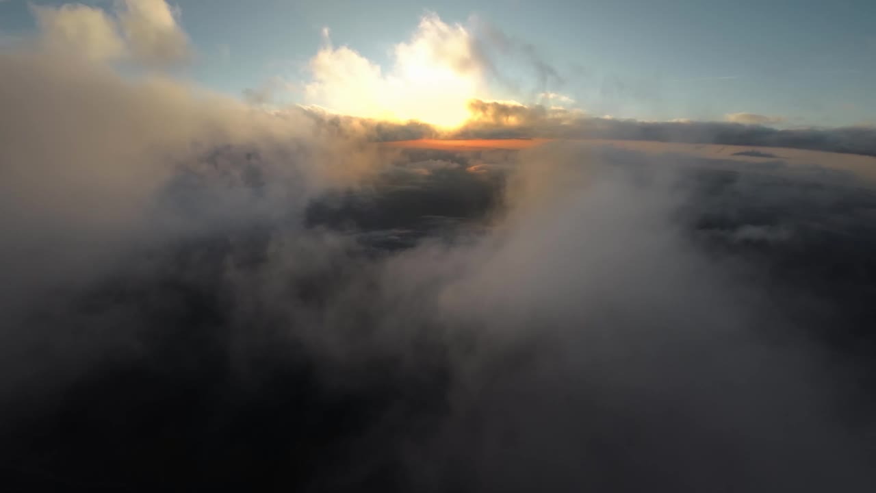 云中壮丽的落日。温暖的太阳在云层中落在地平线后面。日落时在空中飞行，空中或飞机视图，4K视频下载