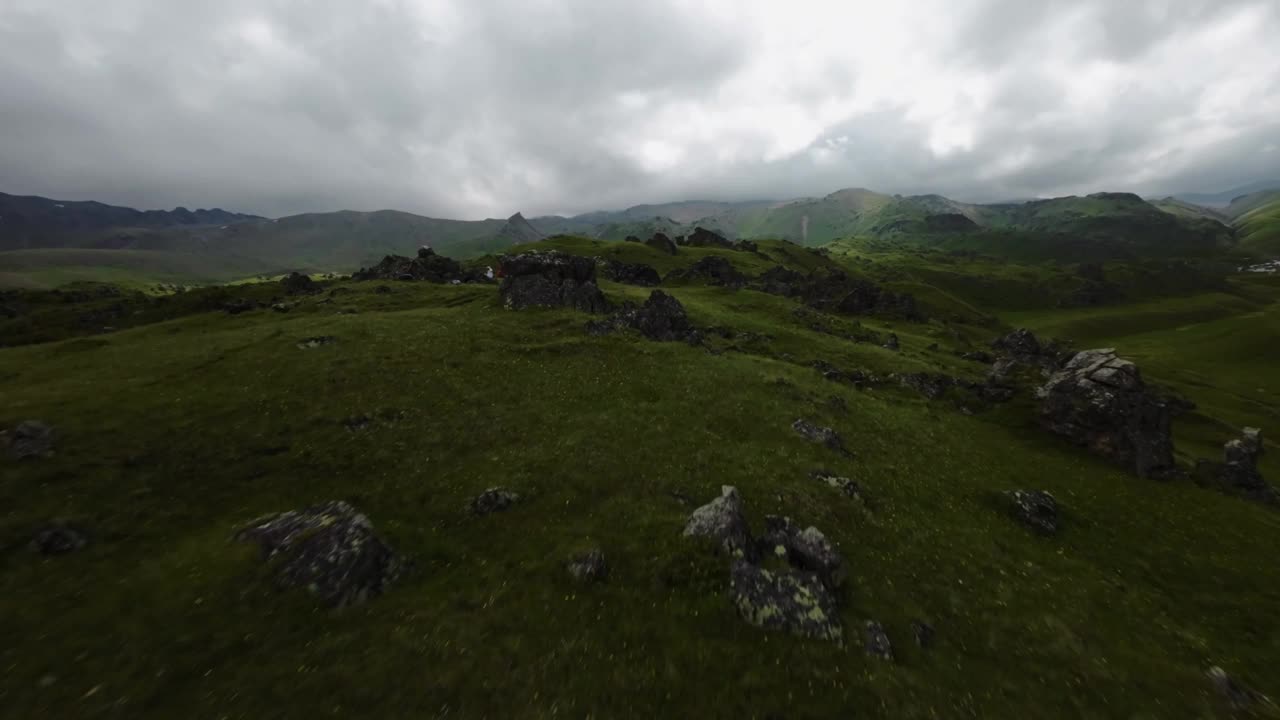 飞越高山，人们散步后放松，美丽的绿色地区与岩石。无人机FPV拍摄，4K视频下载