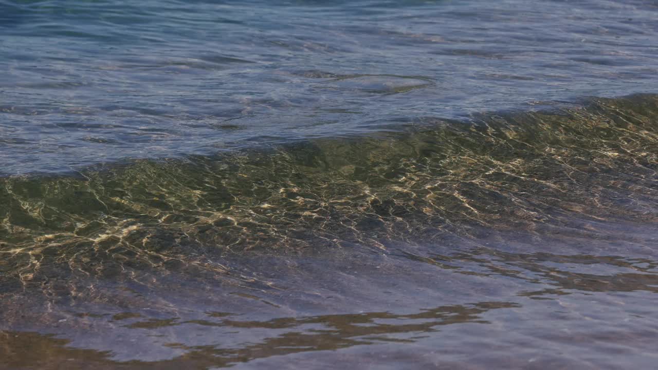 一个晶莹剔透的微型海岸破碎浪在浅水中沿着海岸线撞击。视频素材