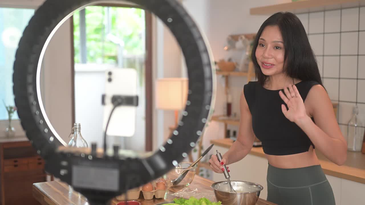 美丽的年轻女子正在准备健康的节食早餐，并为她的频道录制视频。视频素材