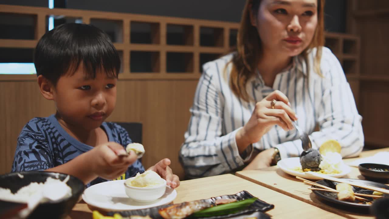 亚洲母亲和女儿坐在日本餐厅后面吃甜点冰淇淋。视频下载