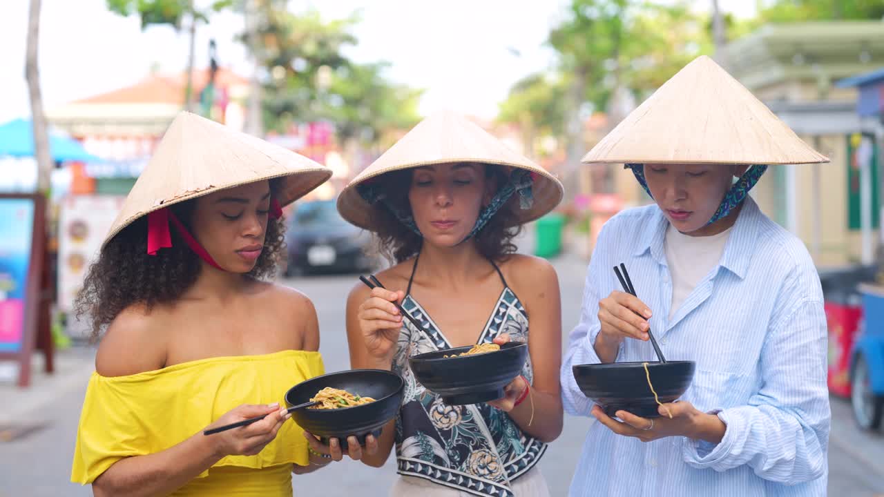 在亚洲旅行的女性戴着越南帽子吃着面条，看起来很开心视频下载