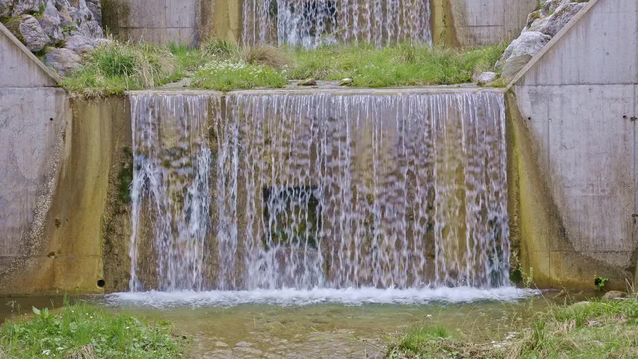 水从人造瀑布倾泻而下，特写。河水绕着石头流动。内瓦尔登州贝肯里德附近的Traeschlibach视频素材