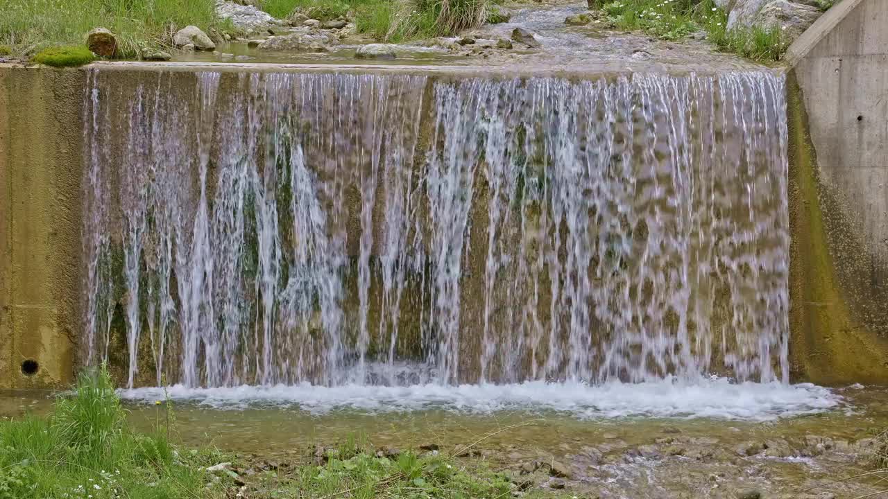 水从人造瀑布倾泻而下，特写。河水绕着石头流动。内瓦尔登州贝肯里德附近的Traeschlibach视频下载