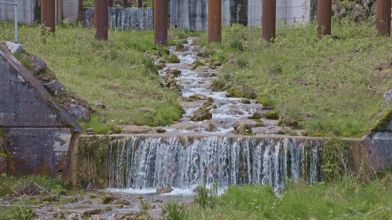 水从人造瀑布倾泻而下，特写。河水绕着石头流动。内瓦尔登州贝肯里德附近的Traeschlibach视频下载