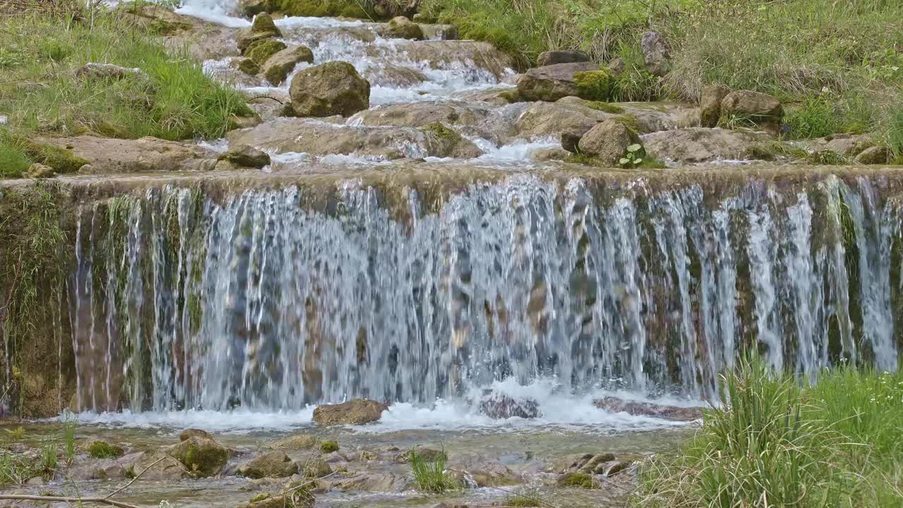 水从人造瀑布倾泻而下，特写。河水绕着石头流动。内瓦尔登州贝肯里德附近的Traeschlibach视频素材