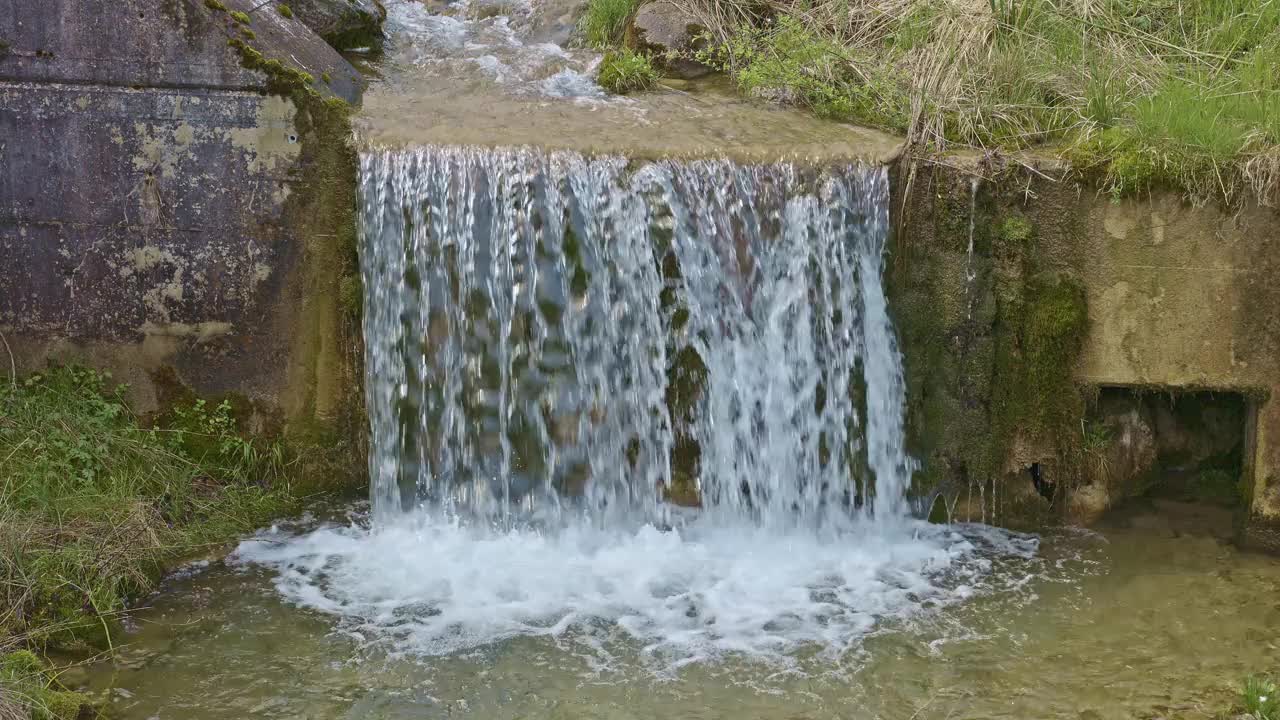 水从人造瀑布倾泻而下，特写。河水绕着石头流动。内瓦尔登州贝肯里德附近的Traeschlibach视频下载