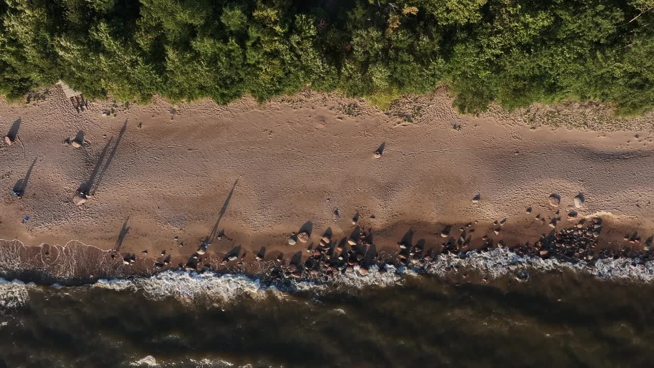 沙滩的海岸，海浪冲刷着沙滩，岩石散落在水边视频素材