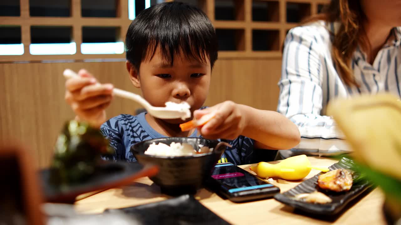 亚洲男孩在日本餐厅吃着美味的蟹肉棒寿司。视频素材