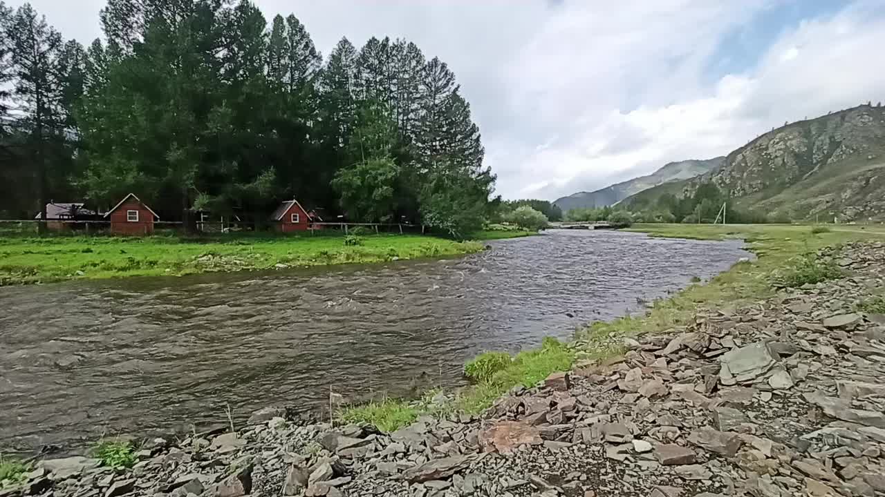 山间河床的一个弯道，在一个阳光明媚的夏日，有茂密的森林和群山环绕的岩石河岸。视频下载